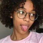 Jovem mulher de cabelo cacheado e óculos, blusa rosa, inscrita do PW Club